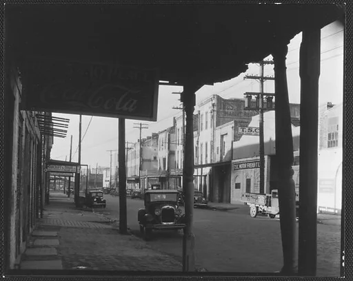 [Parked Cars and Warehouse Buildings on Cobblestone Street, From Under Colonnade, New Orleans, Louisiana?]
