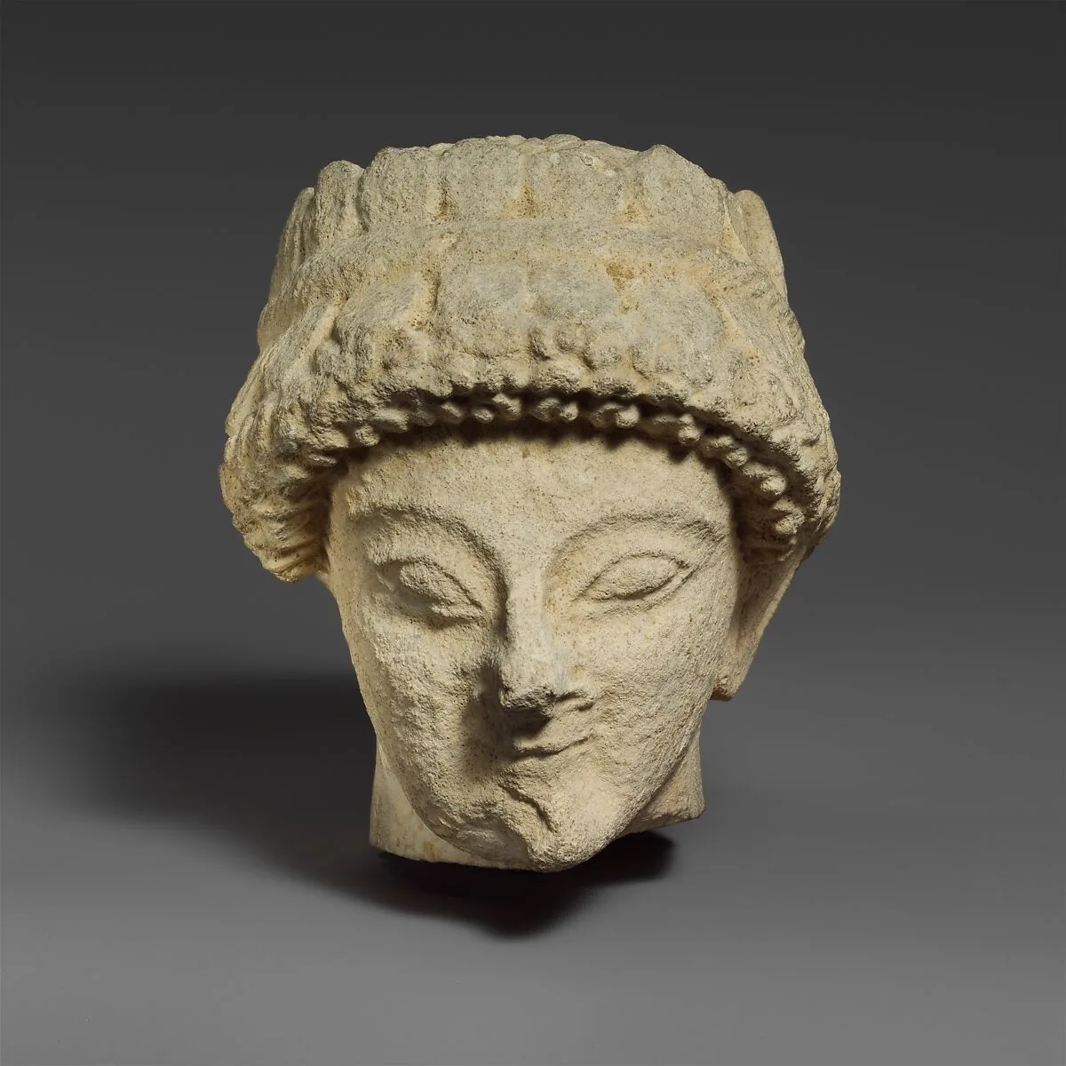Limestone head with of a beardless male with a wreath of leaves — Unknown