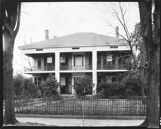 [Two Story House Behind Iron Grillwork Fence]