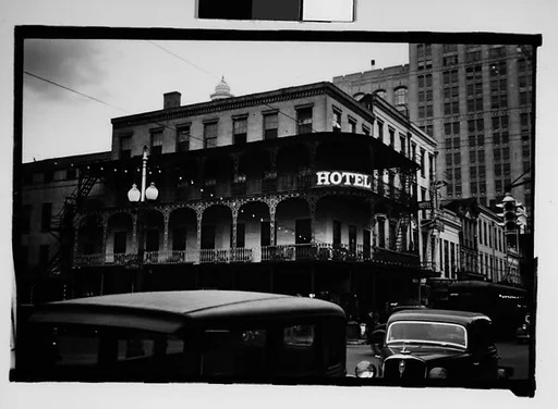 [Cast-Iron Balconied Hotel with Passing Cars in Foreground, New Orleans, Louisiana]