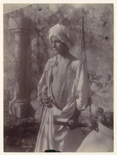 [Young Man in White Robe and Head Gear Holding Scabbard, Sicily, Italy]