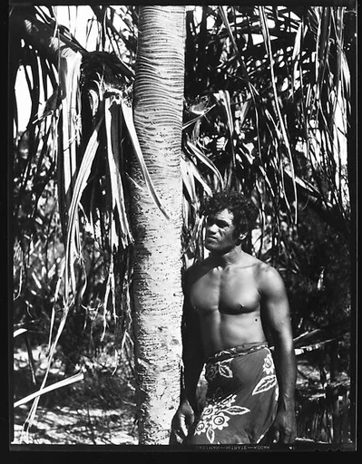 [South Seas: Man in Sarong Standing Next to Tree]