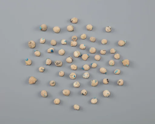 Tray of clay balls with embedded faience ring beads