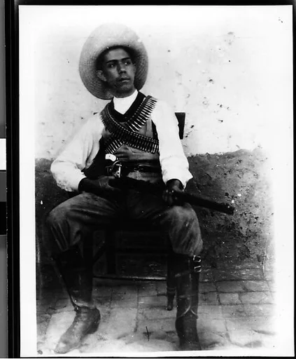 [Newsphoto of Seated Man with Shotgun and Ammunition]