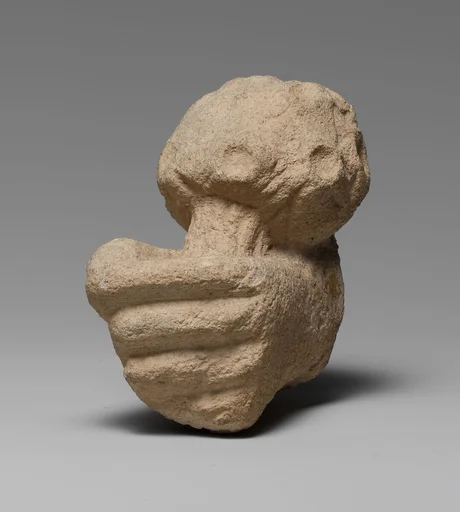 Limestone statue fragment of a left hand holding a bunch of daisies