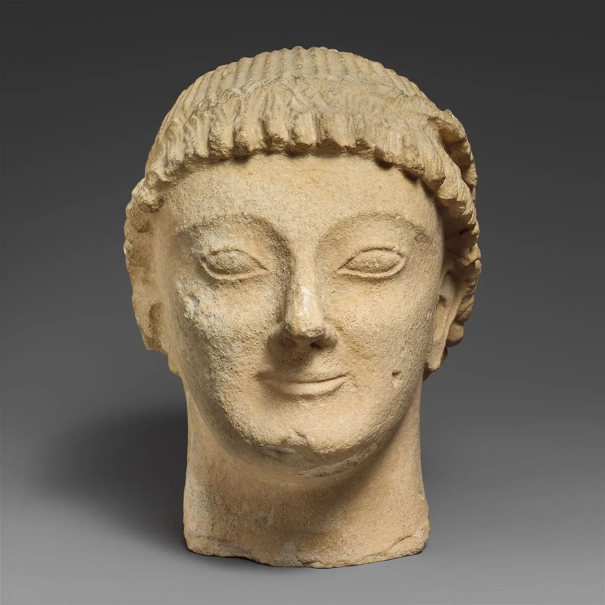 Limestone head of a beardless male votary with a wreath of rosettes — Unknown