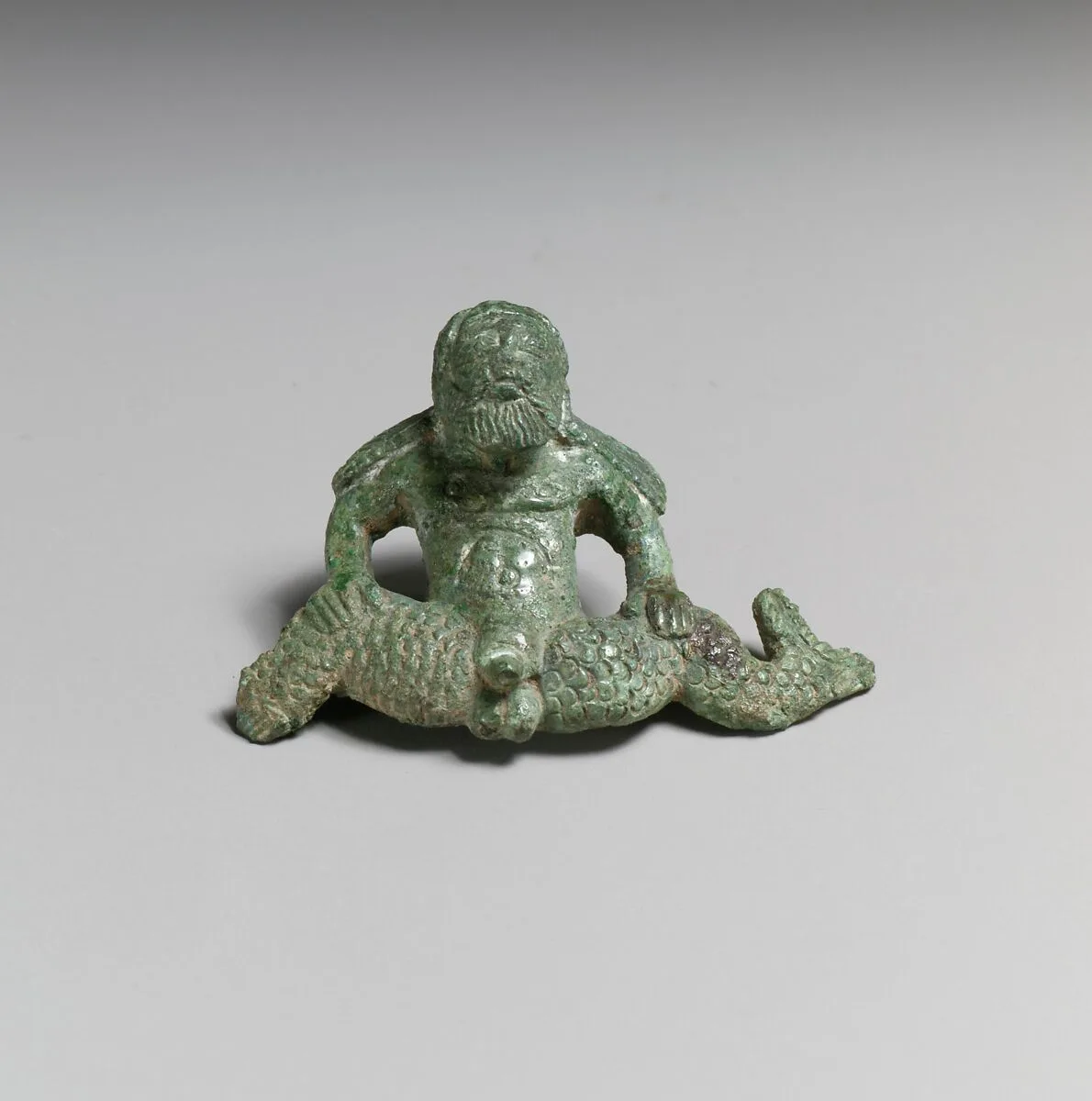 Bronze helmet attachment in the shape of a triton — Unknown