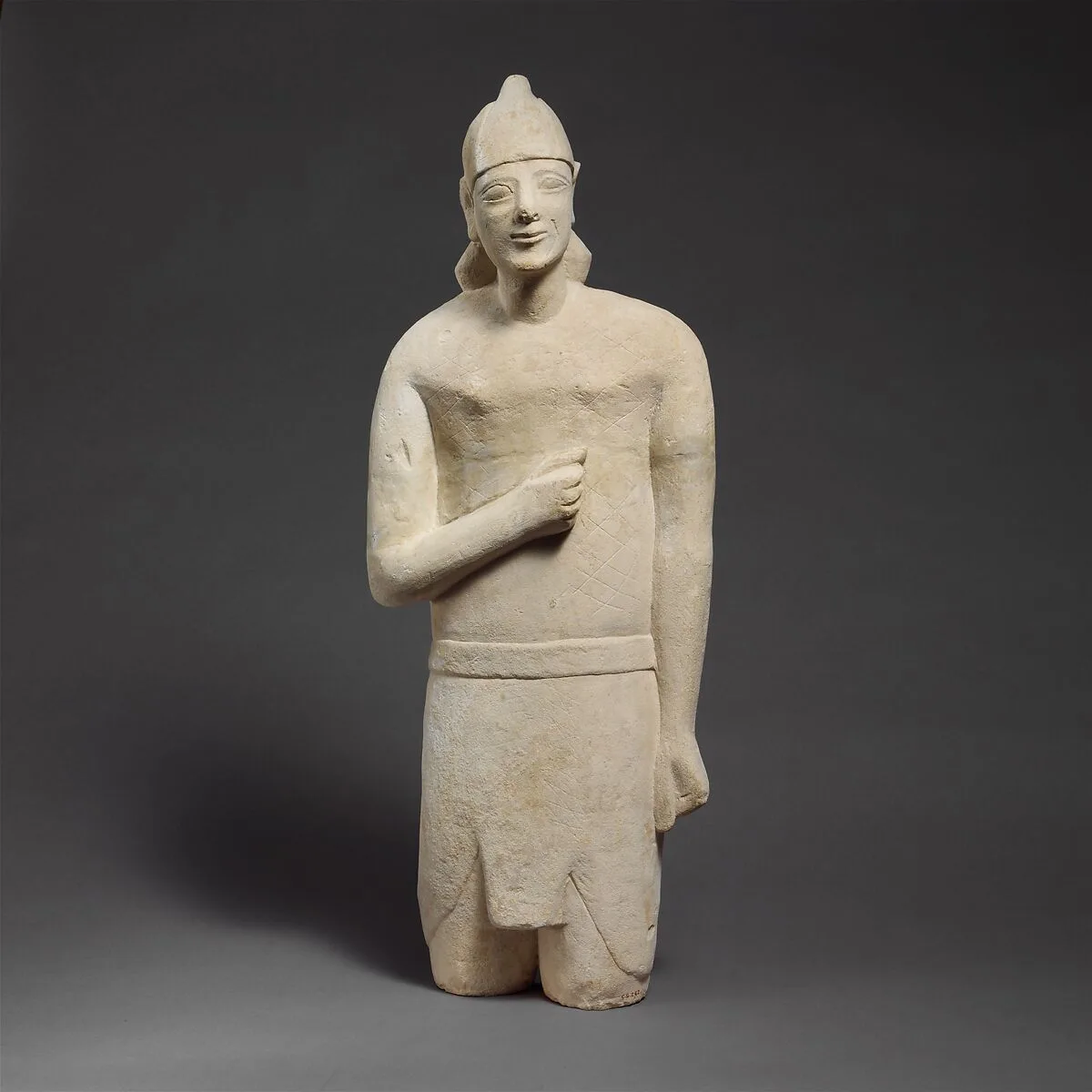 Limestone statuette of a beardless male votary in Egyptianizing dress wearing a helmet — Unknown