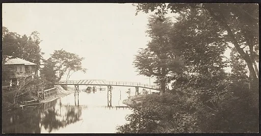 [View of a Bridge leading to a House over a Body of Water]