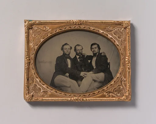 [Three Seated Men with Arms Around Each Other]