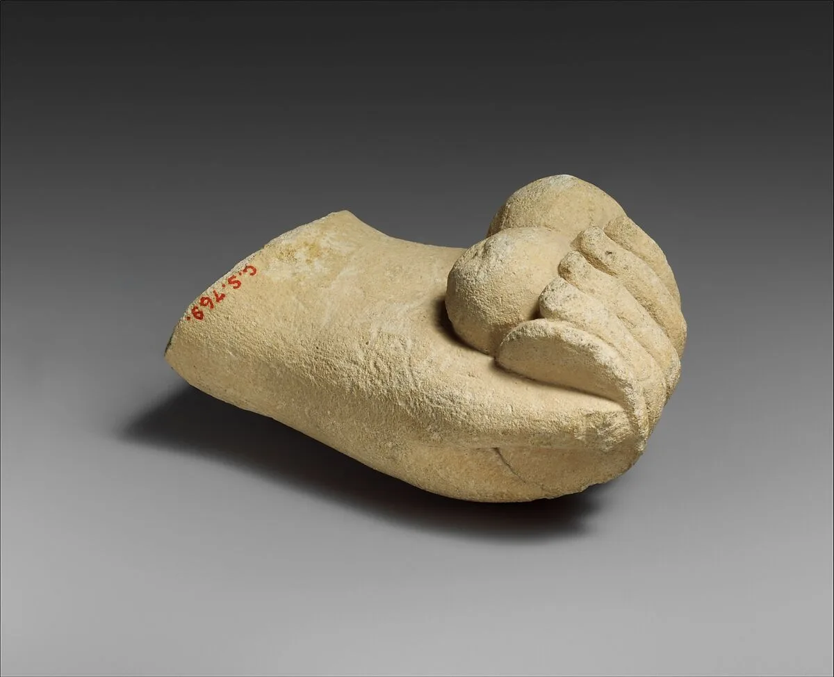 Limestone hand holding a disk and pieces of fruit — Unknown