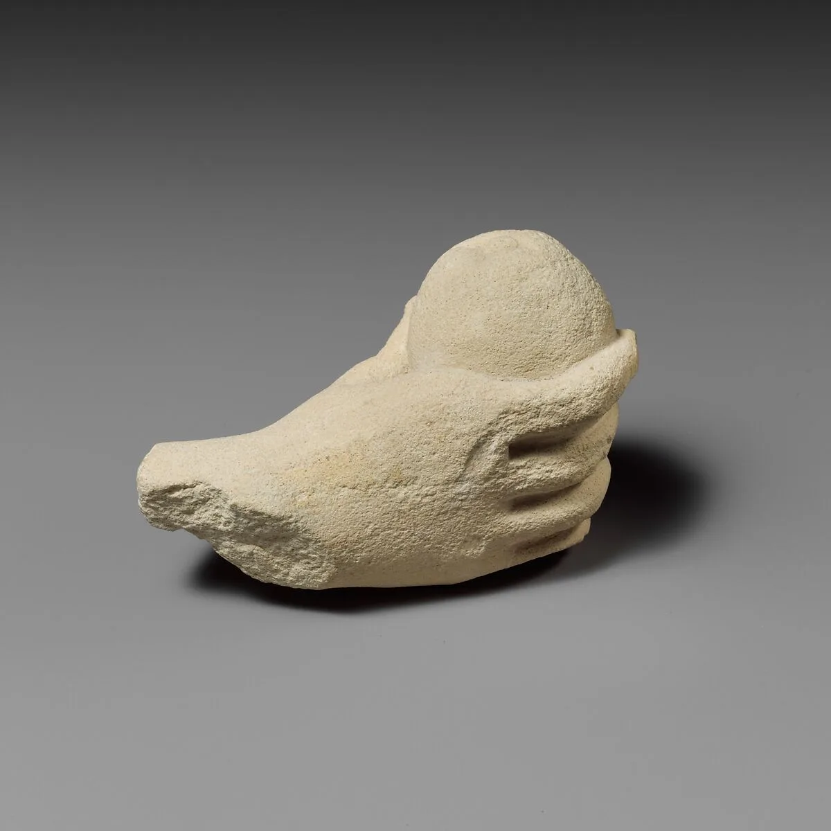 Limestone hand holding a piece of fruit — Unknown