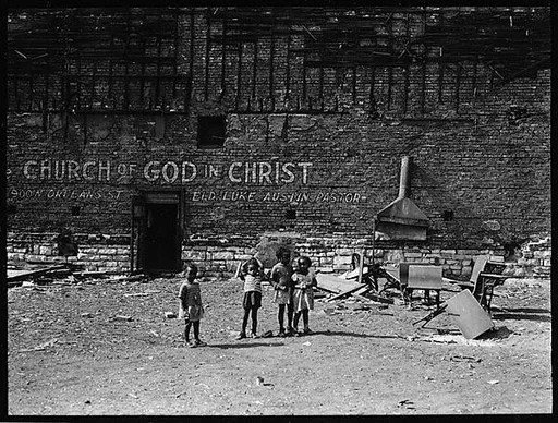 [Children in Abandoned Lot in Front of Brick Wall with Sign for "Church of God", Chicago, Illinois]