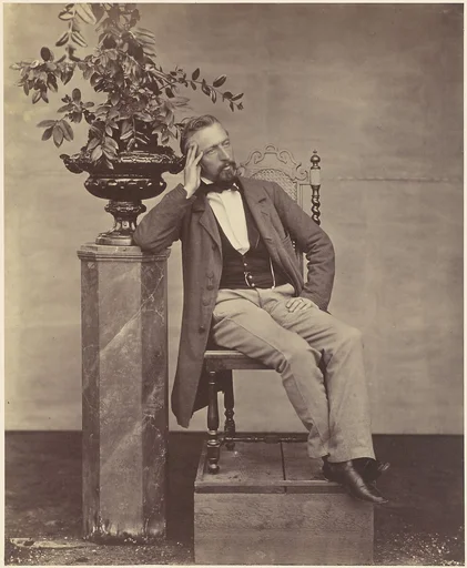[Mathias Häusermann seated with elbow on pedestal holding a vase of flowers]