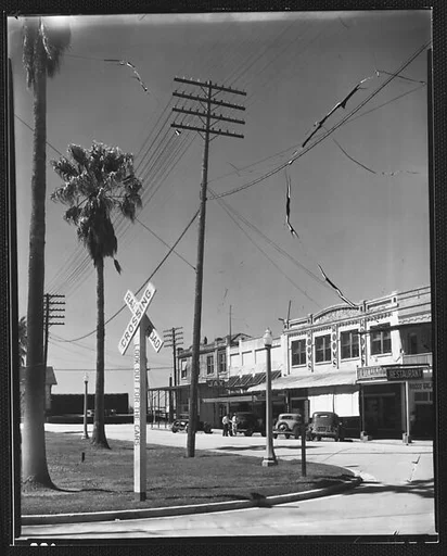 [Main Street Shopfronts and Parked Cars with Railroad Crossing Sign in Foreground, Morgan City, Louisiana]
