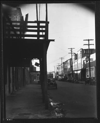 [Parked Cars and Warehouse Buildings on Cobblestone Street With Colonnade in Foreground, New Orleans, Louisiana?]