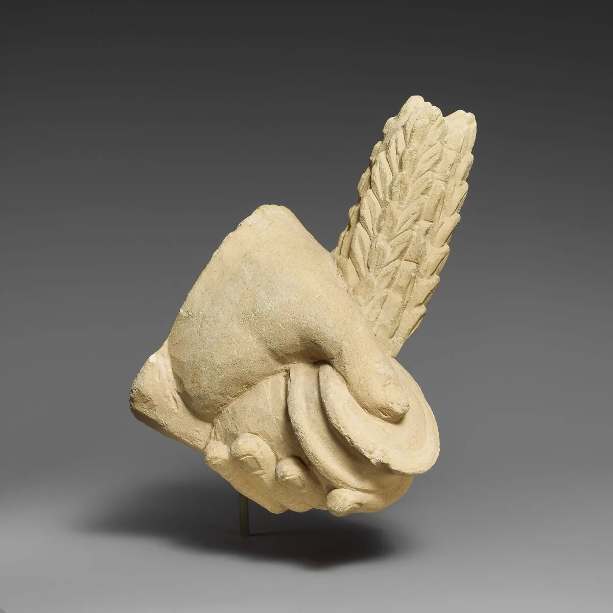 Limestone hand holding a pyxis and a branch of leaves — Unknown