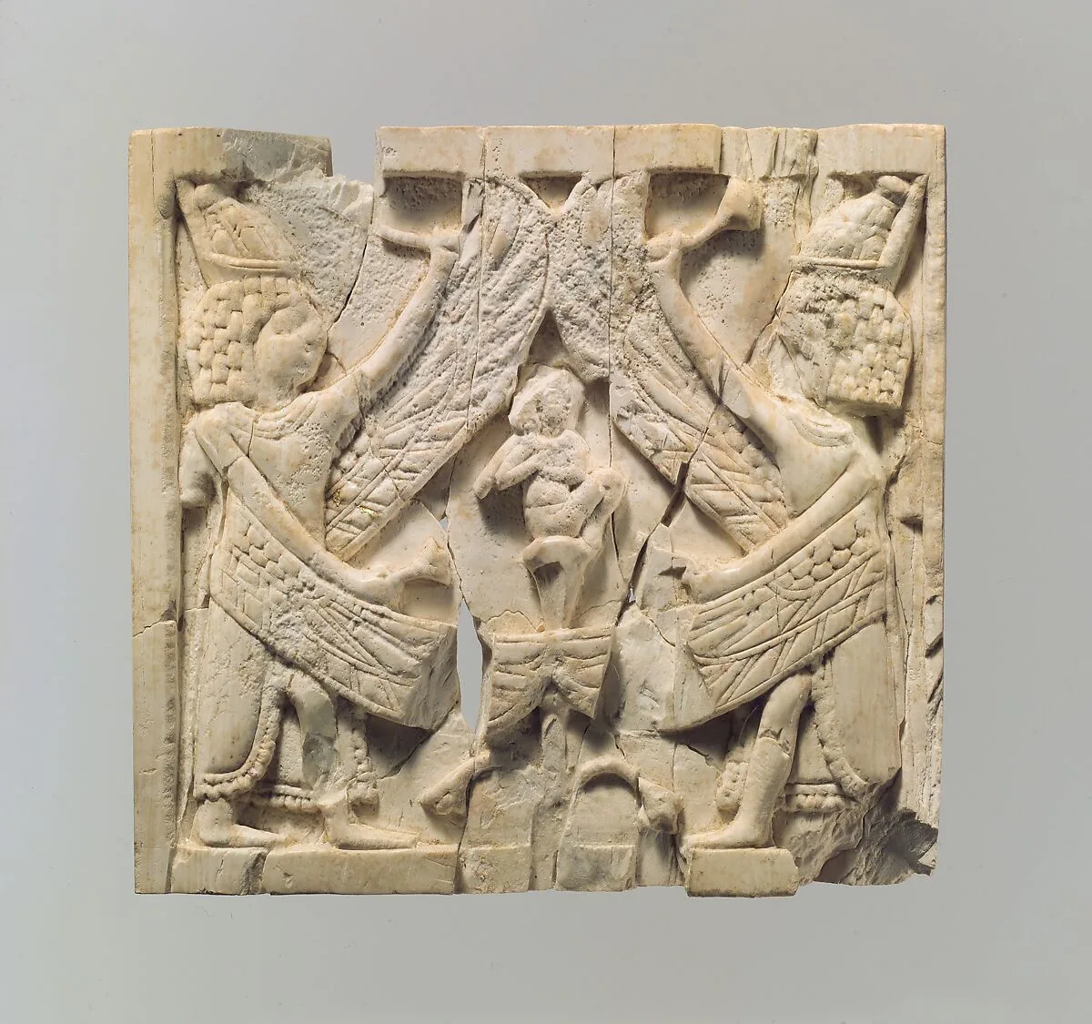 Furniture plaque carved in relief showing two winged, male figures flanking an infant on a lotus flower — Unknown