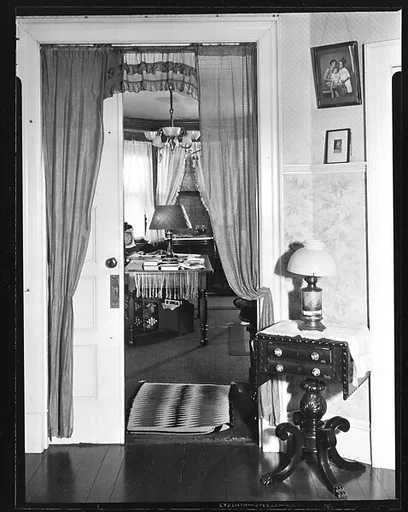 [Interior Showing Doorway to Library with Family Photographs and Table in Foreground]