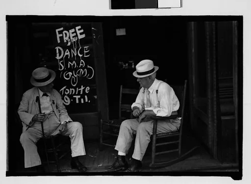 [Two Elderly Men in Straw Hats Seated on Porch Before "Free Dance" Sign, Greensboro?, Alabama]