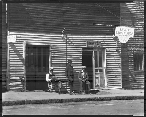 [Men on Sidewalk in Front of New Deal and Savoy Barber Shops, Vicksburg, Mississippi]