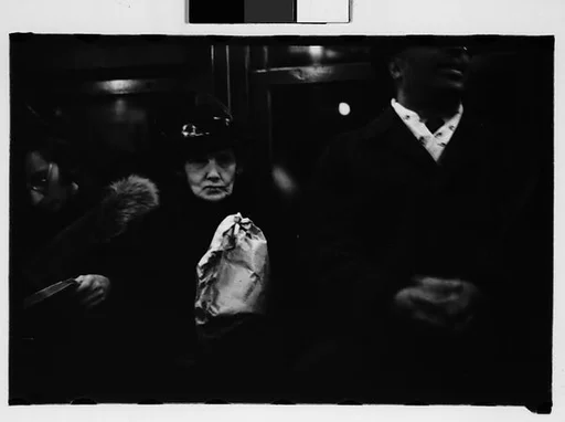 [One 35mm Film Frame: Subway Passengers, New York City: Elderly Woman Clutching Paper Bag, Seated Between Man and Woman]