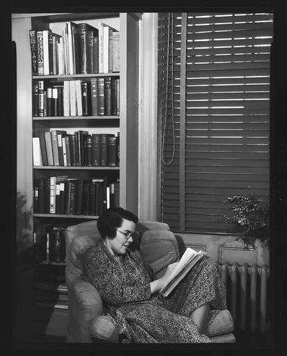 [Unidentified Woman Reading in Armchair in Library]