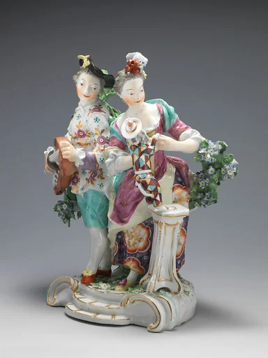 Youth playing hurdy-gurdy, girl teaching dog dressed as harlequin to dance