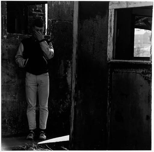 [Boy Standing in Room, with Hand to Face]