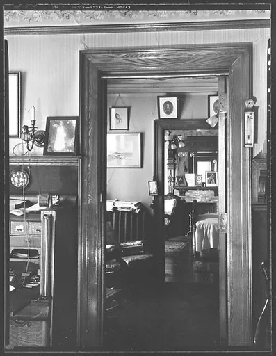 [Interior Showing Family Photographs Around Doorways and on Fireplace Mantle]
