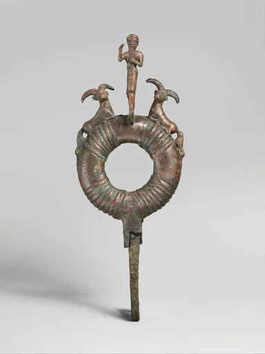 Top of standard with male figure and flanking ibexes attacked by dogs