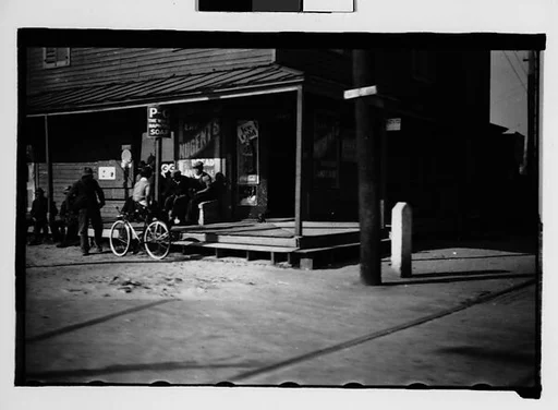 [Men Seated on Corner Store Porch, From Automobile, Savannah, Georgia]