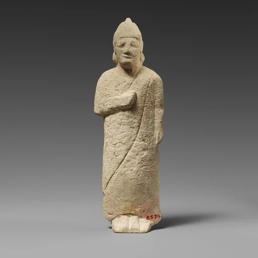 Limestone statuette of a beardless male votary with a conical helmet
