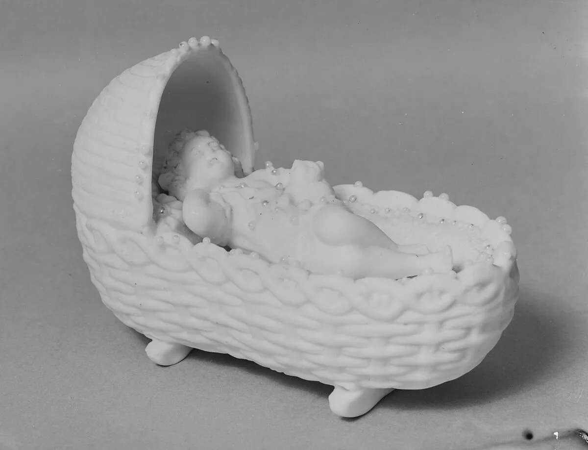 Figure of a Baby in a Cradle Holding a Kitten — Unknown
