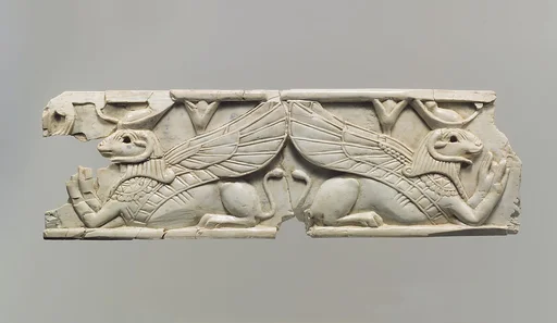 Furniture plaque carved in relief with two addorsed, ram-headed sphinxes