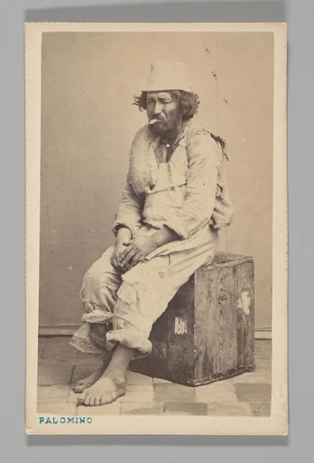 [Studio Portrait: Man Seated on Wooden Box ]