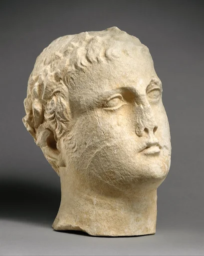 Limestone head of beardless male votary with wreath of leaves