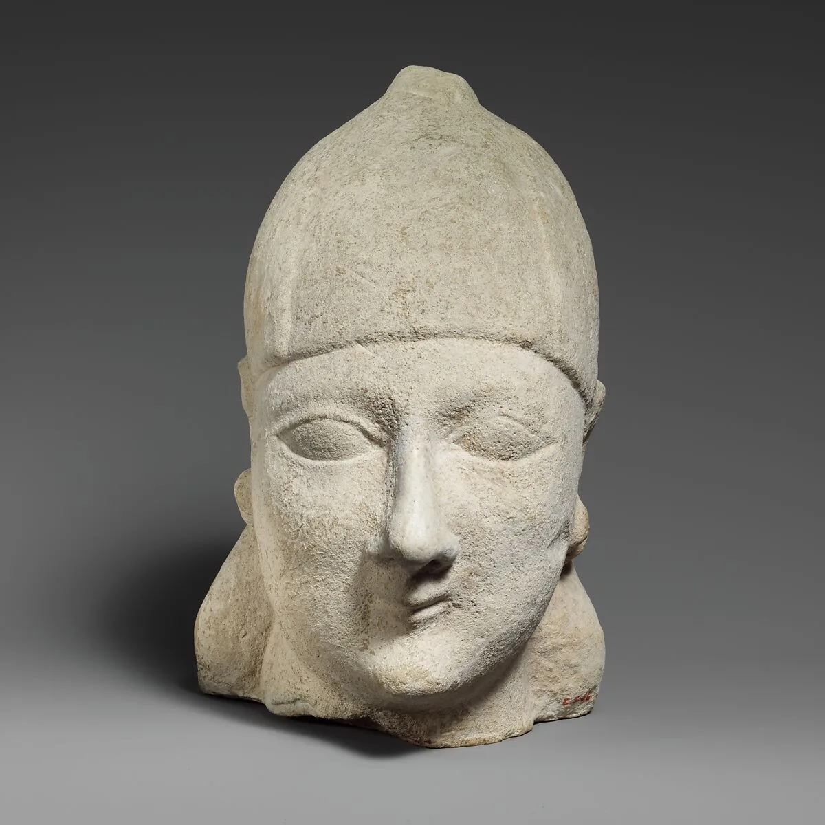 Limestone head of a beardless male wearing a conical helmet — Unknown