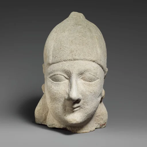 Limestone head of a beardless male wearing a conical helmet