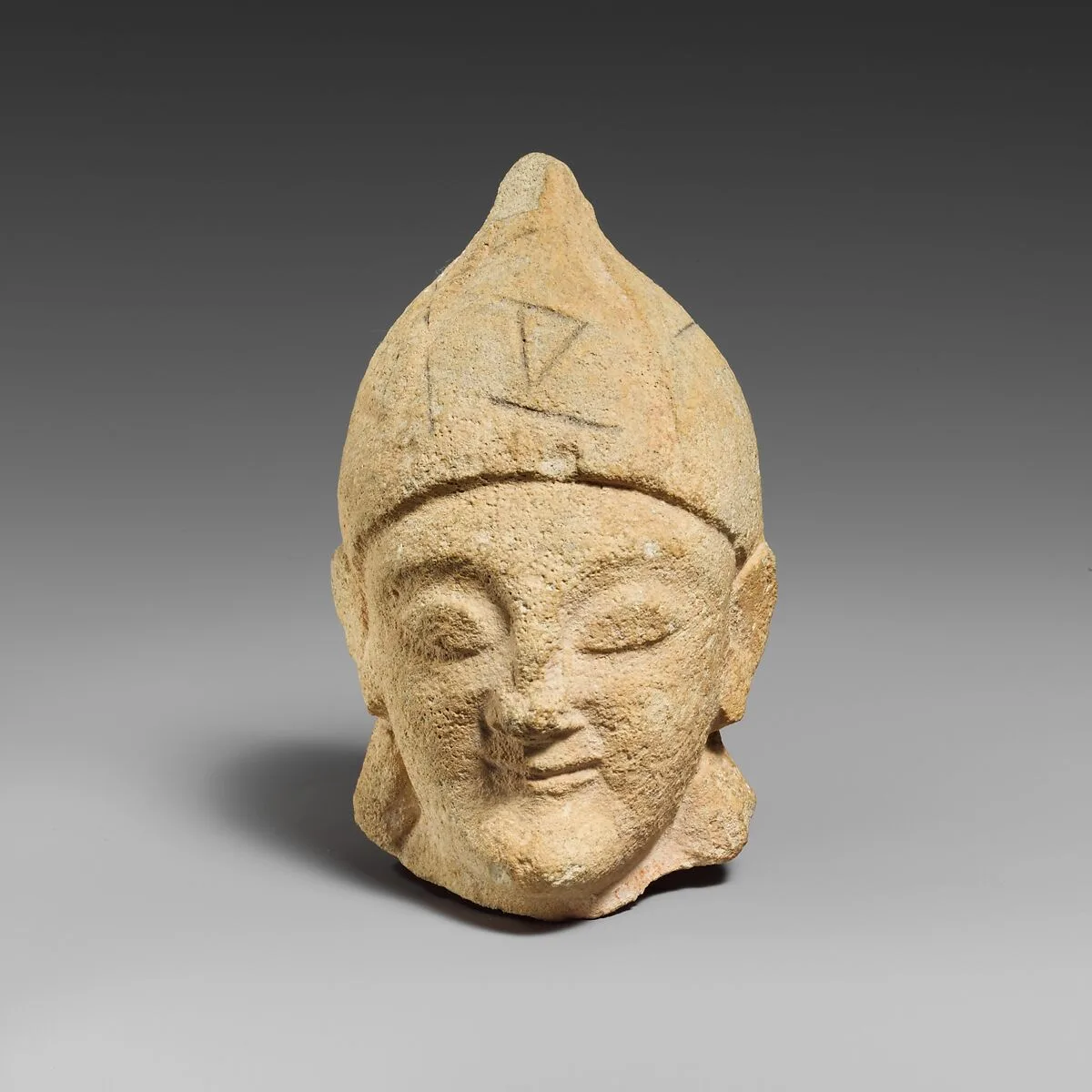 Limestone head of a beardless male with a helmet of Greek type — Unknown