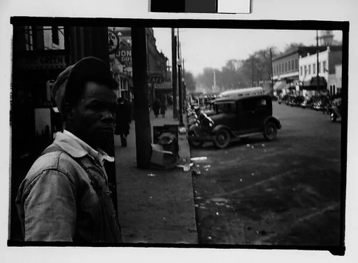 [Man Leaning on Lamppost on Main Street, Milledgeville, Georgia]