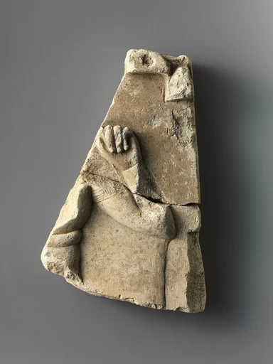 Fragment of relief plaque with a child god, inscribed on reverse