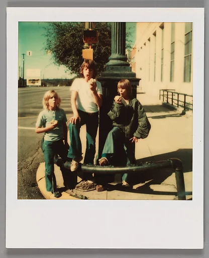 [Three Boys Eating Apples On Street Corner]