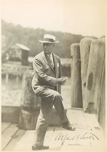[Copy of Signed Photograph of Alfred E. Smith, Governor of New York, Standing on Dock in Suit and Hat, Holding Sandwich]