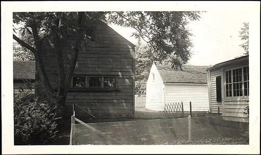 [Clapboard House and Barns Behind Wire Fence]