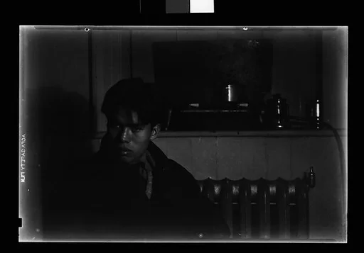 [Young Man in Overcoat Seated in Front of Radiator]