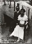 Stylish couple seated before stairs