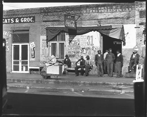 [Groups of Men Seated on Bench and Standing Around Shop Doorway, Selma, Alabama]