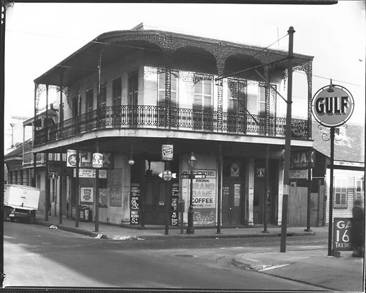 [Cast-Iron Balconied House with Ground Floor Advertisements and Gulf Filling Station Sign in Foreground, New Orleans, Louisiana]
