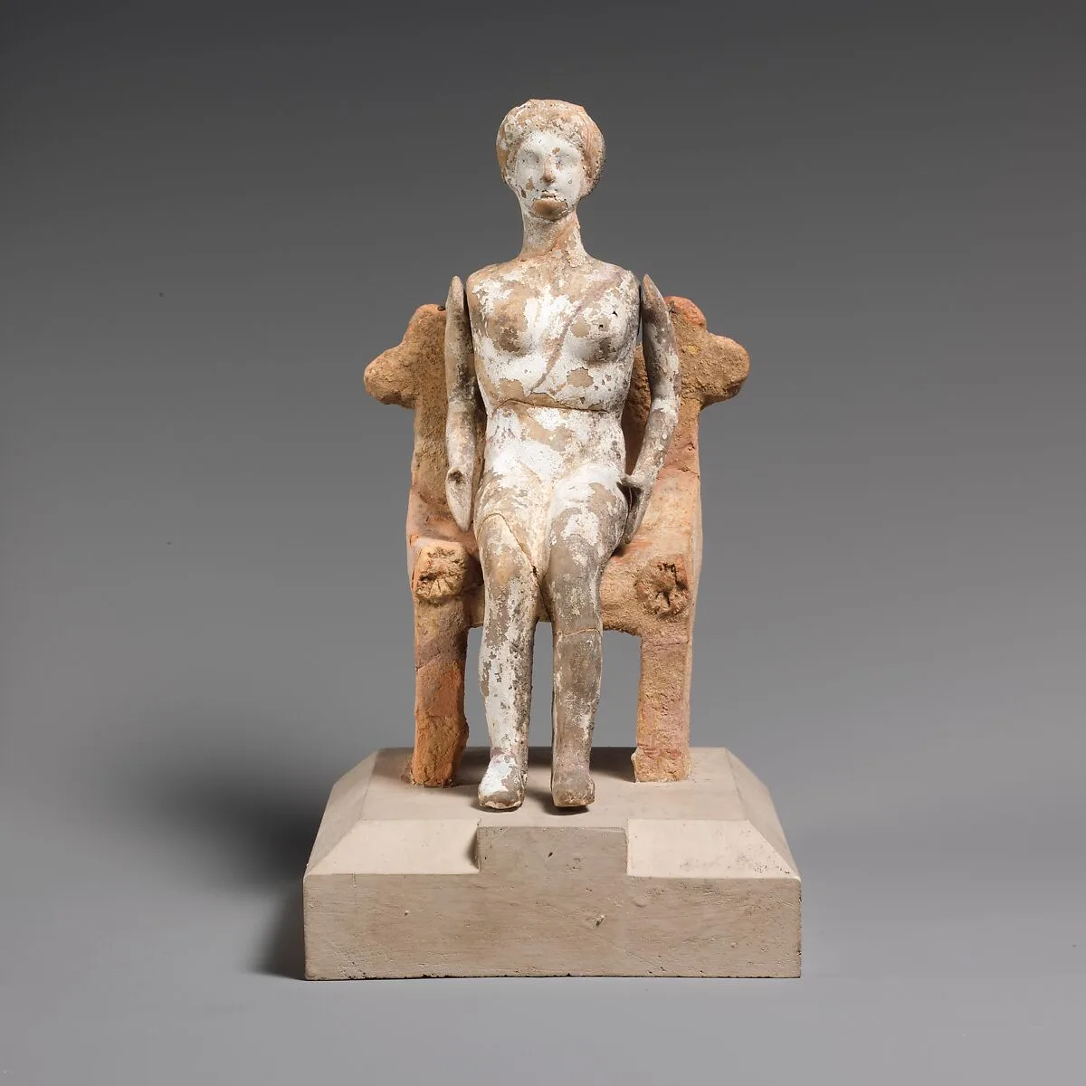 Terracotta doll with articulated arms seated on a chair — Unknown